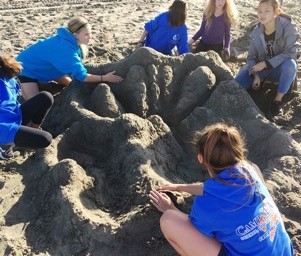 A group of people sitting on top of sand.