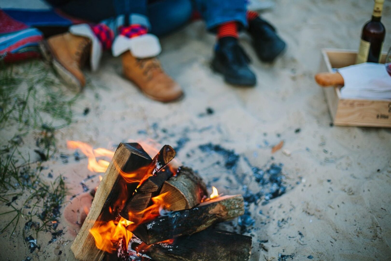 A fire is burning on the ground with people sitting in front of it.