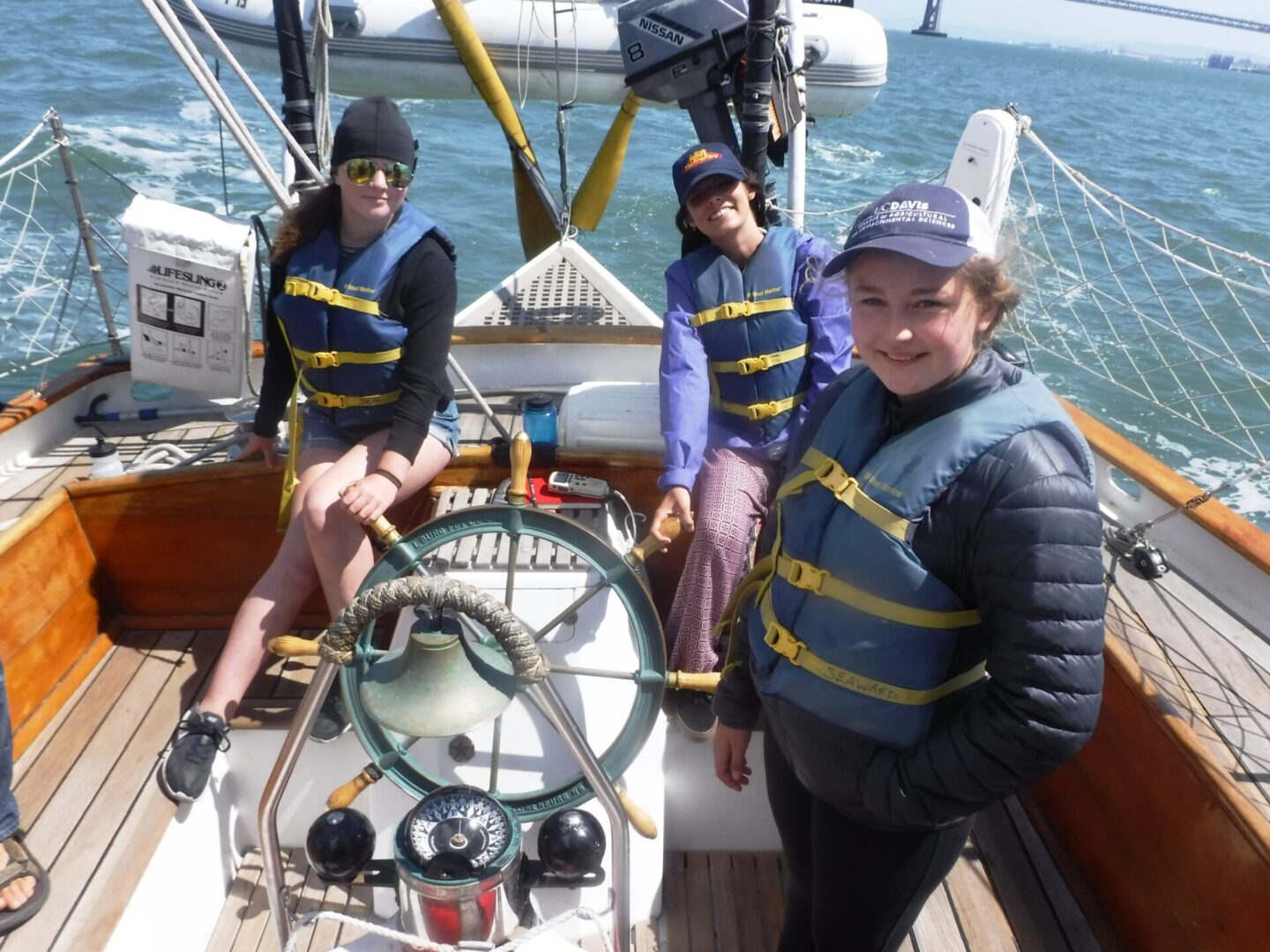 Three young people on a boat in the water.