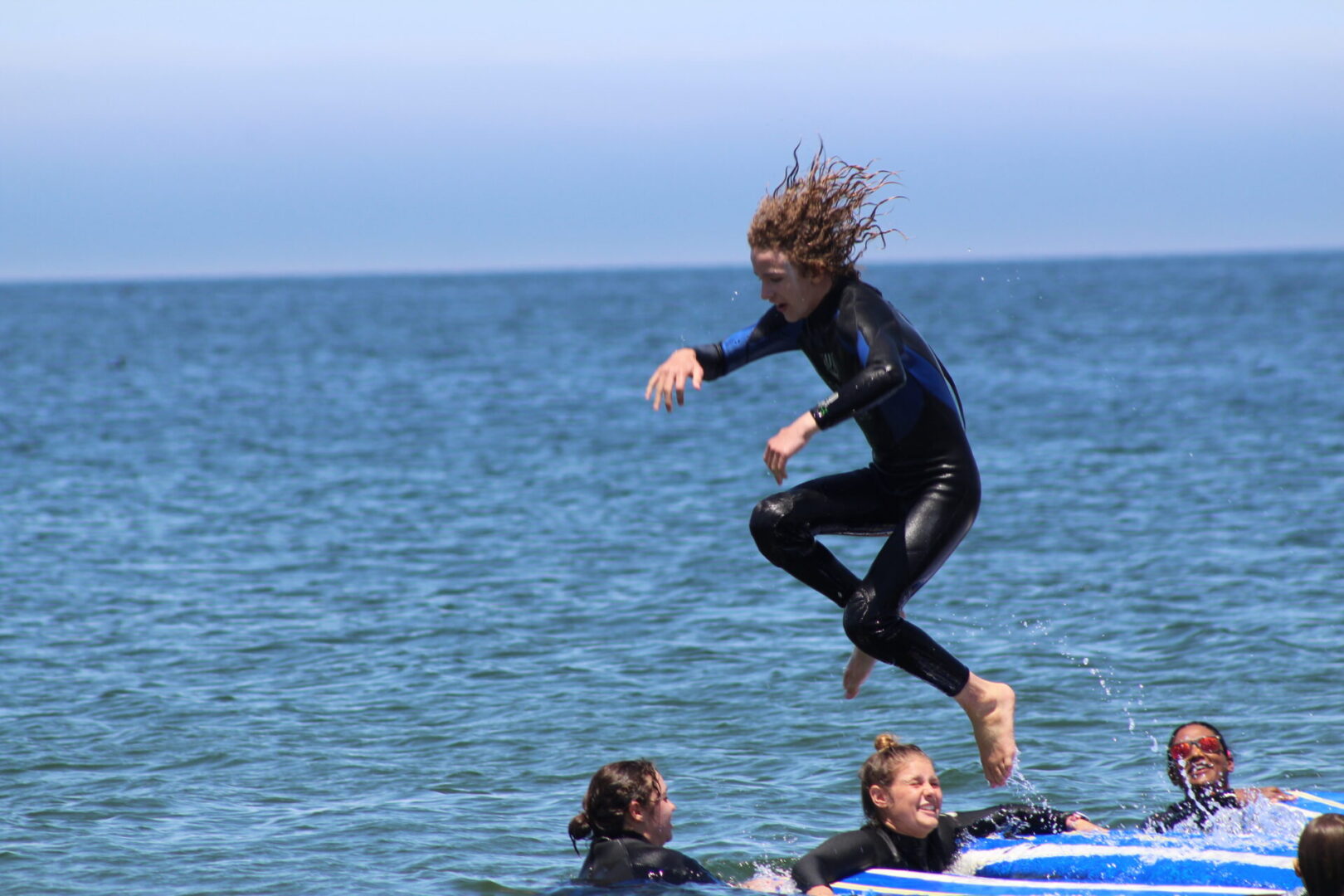 A woman jumping off of a surfboard in the ocean.