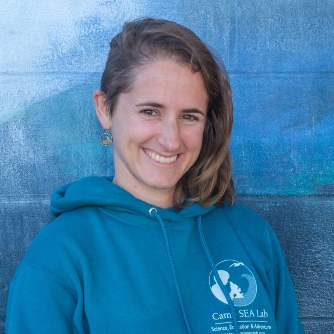 A woman in blue hoodie smiling for the camera.