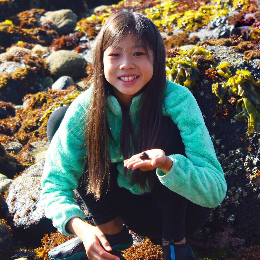 A young girl is sitting on the rocks