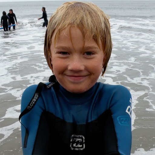 A young boy in wet suit on the beach.